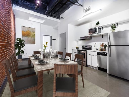 a dining room with a table and chairs and a kitchen in the background