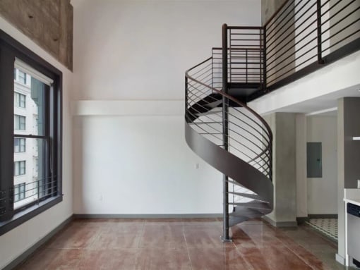 Downtown Los Angeles Lofts - Broadway Lofts - Living Room With High Ceilings, Large Windows With City Views, And A Spiral Staircase
