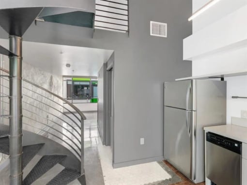 a kitchen with a stainless steel refrigerator next to a spiral staircase