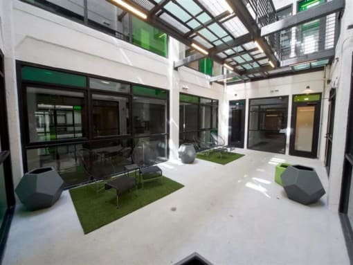 Downtown Los Angeles, CA, Apartments - Broadway Lofts - Outdoor Courtyard with Chairs, Turf Grass Mats, And Pots.