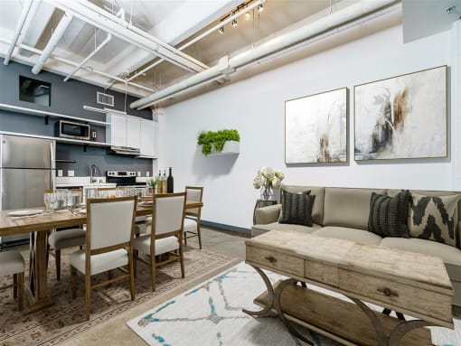 a living area with a couch table and chairs and a kitchen in the background