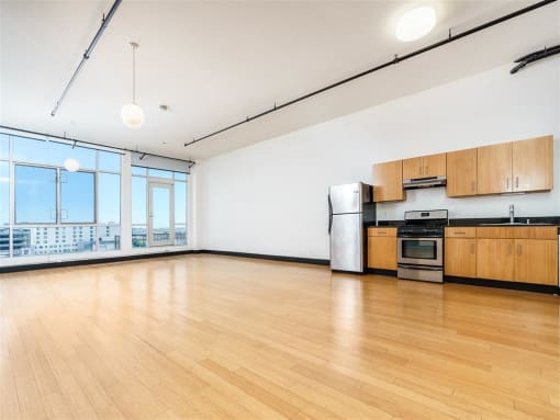 Downtown Los Angeles, CA Apartments for Rent - Mercantile Lofts - Open Concept Kitchen With Stainless Steel Appliances, Wood Cabinetry, Hardwood Floors, And Oversized Windows With City Views.