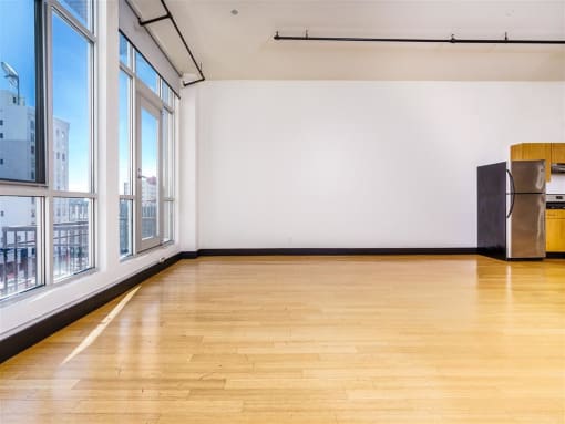 an empty room with wood floors and large windows