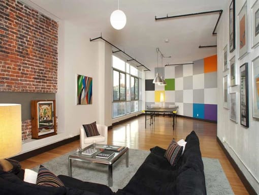 Apartments Near The Last Bookstore - Mercantile Lofts - Living Room With Bamboo Wood Flooring, Floor-to-Ceiling Windows with Beautiful Natural Light, City Skyline Views, And Exposed Brick Walls.