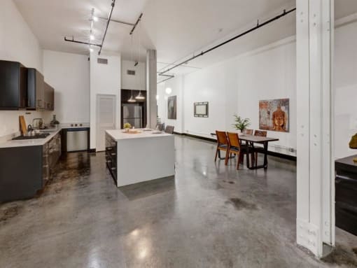 a kitchen and dining room with white walls and concrete floors