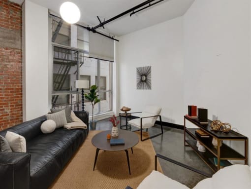 a living room with a leather couch and a coffee table in front of a window