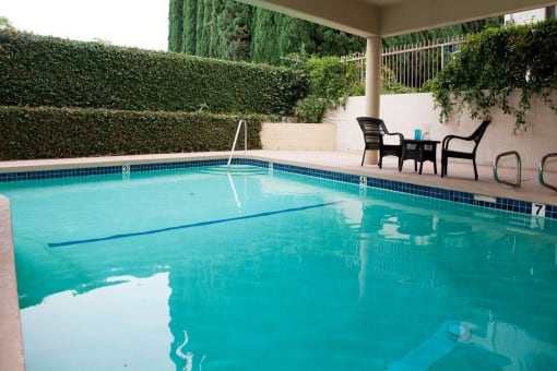the pool is next to a patio with chairs and a table