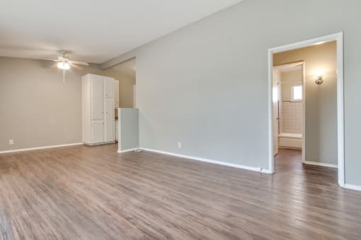 Living room wood-style floors throughout the unit, dining area with ceiling fan on the left