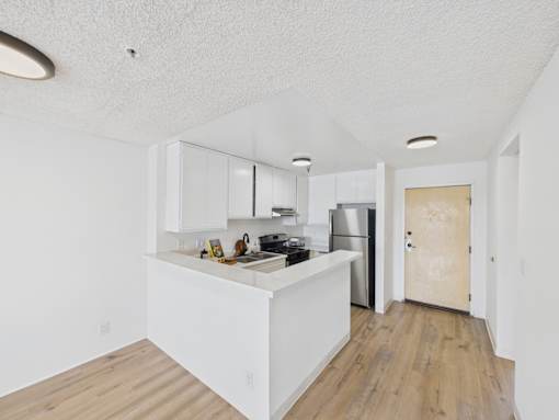 A kitchen with white cabinets and a wooden floor.