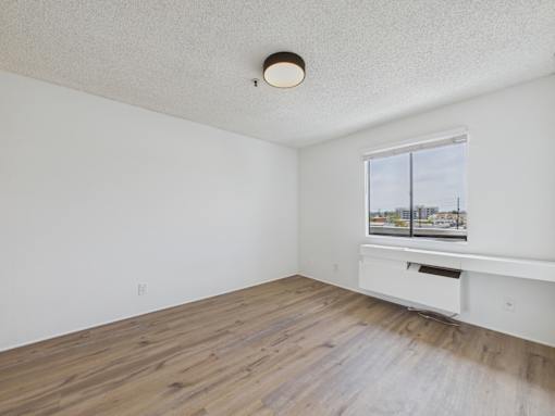 Empty room with a window and wooden floor.