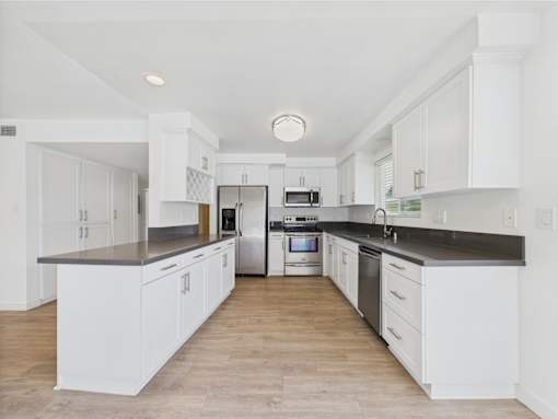 A kitchen with white cabinets and black countertops.