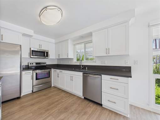 A kitchen with white cabinets and a black countertop.