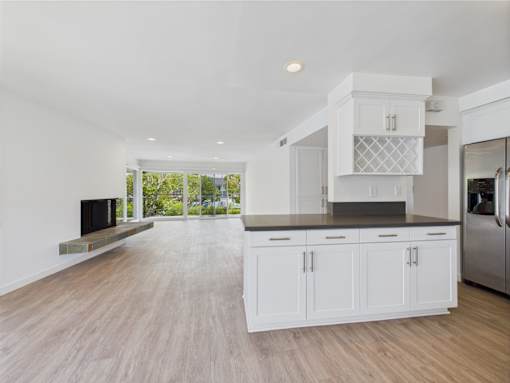A modern kitchen with white cabinets and a wooden floor.