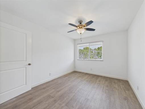 A room with a ceiling fan and a window showing a view of trees.