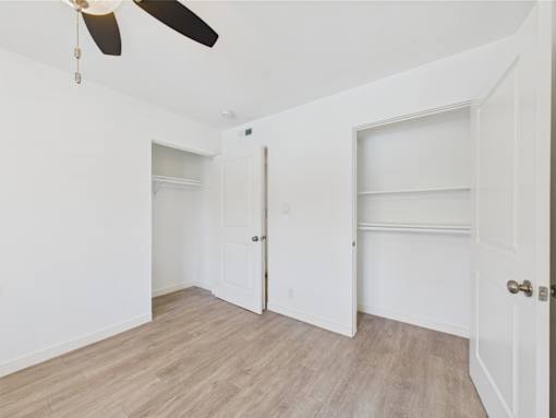 A room with a ceiling fan and two doors.