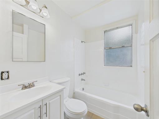 A white bathroom with a toilet, sink, and bathtub.