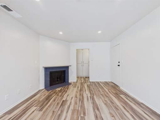 A room with a fireplace and wood flooring.