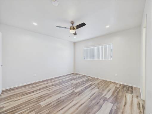A room with a ceiling fan and wooden flooring.