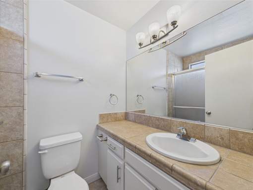 A bathroom with a toilet, sink, and mirror.