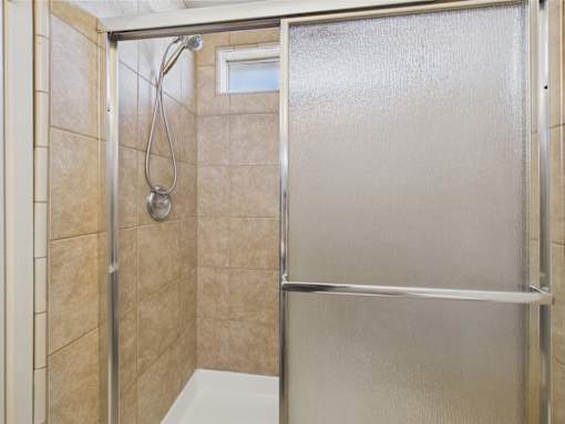 A shower area with a glass door and a shower head.