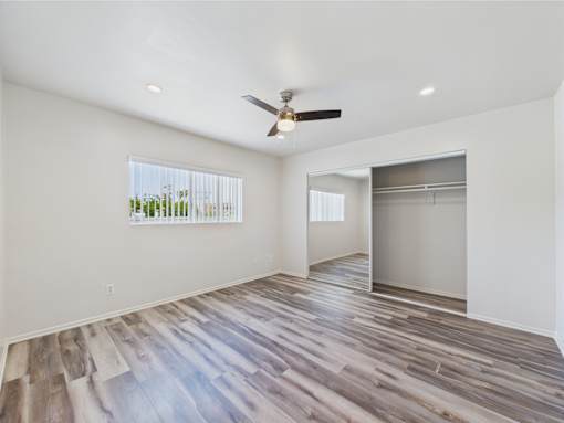 A room with a ceiling fan and sliding glass doors.
