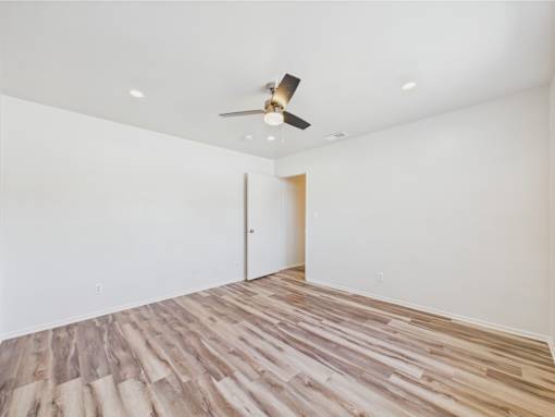 A room with a ceiling fan and wooden flooring.