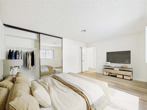 A bedroom with a large bed and a mirrored closet.