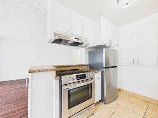 A kitchen with a stove top oven and a refrigerator.