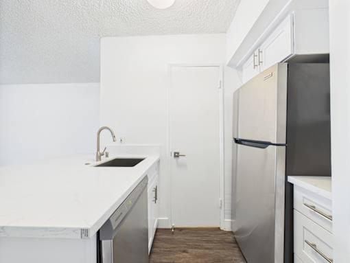 A kitchen with a white counter top and a black refrigerator.