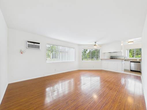 A large empty room with wooden floors and white walls.