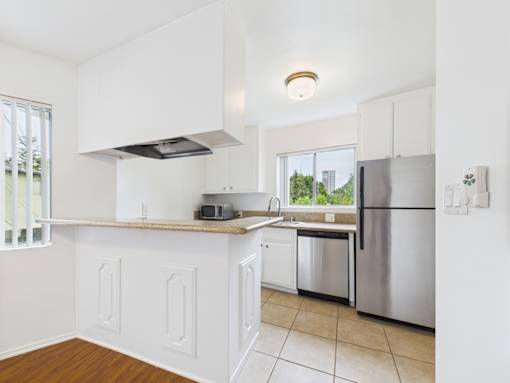 A kitchen with white cabinets and a stainless steel refrigerator.