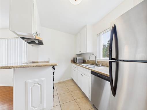 A kitchen with a stainless steel refrigerator and white cabinets.