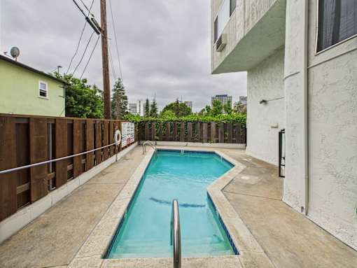 A small pool in a backyard with a concrete floor.