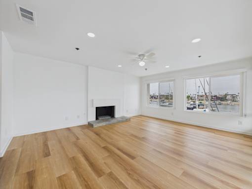 A spacious room with a fireplace and wood flooring.