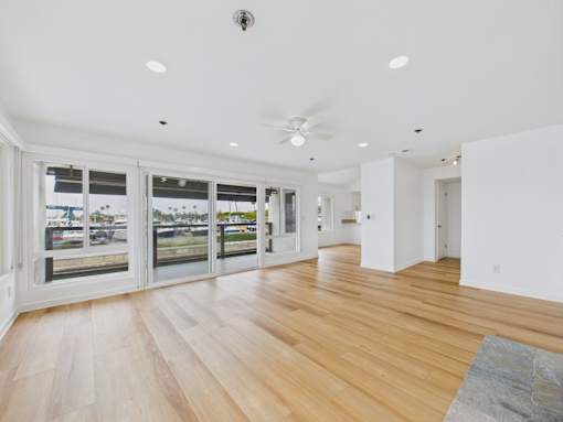 A spacious room with wooden floors and a ceiling fan.