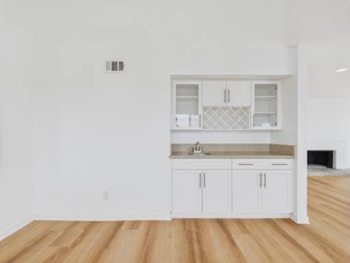 A kitchen with white cabinets and a wooden floor.