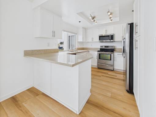 A kitchen with white cabinets and a wooden island.