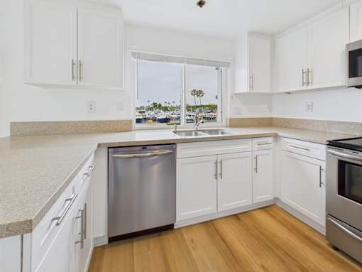 A kitchen with white cabinets and a stainless steel dishwasher.