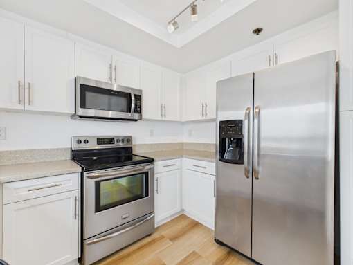 A kitchen with a stainless steel refrigerator, microwave, oven, and cabinets.