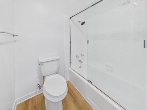 A white toilet sits next to a glass shower stall.