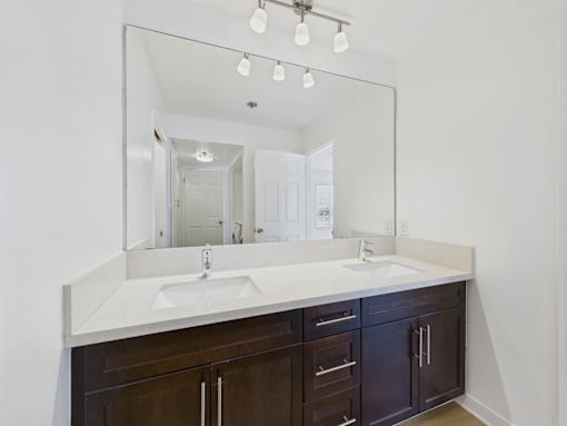 A bathroom with a white countertop and brown cabinets.