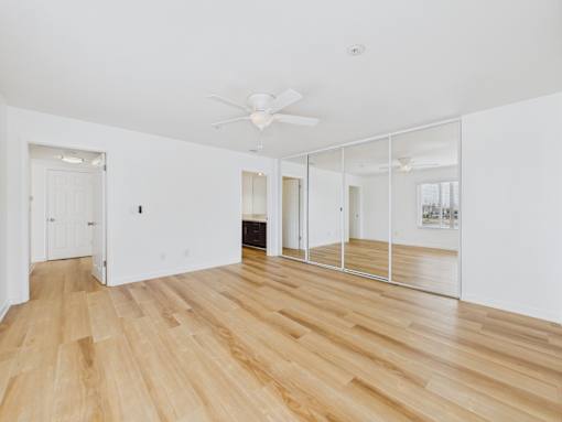 A room with wooden floors and a white ceiling with a fan.