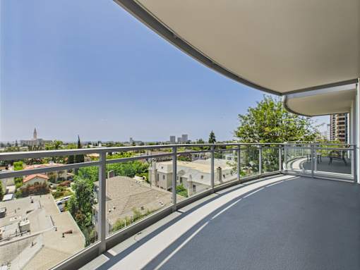 A long balcony with a metal railing and a grey floor.