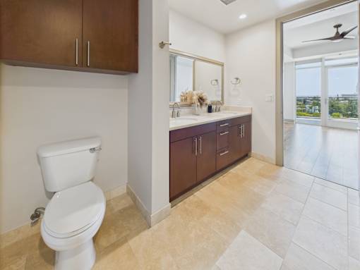 A bathroom with a white toilet and brown cabinets.
