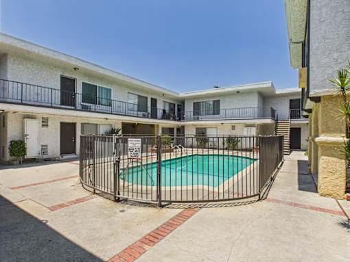 A pool surrounded by a fence in front of a building.