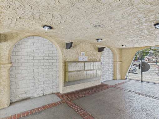 A white brick wall with a stone archway and a sign on the wall.