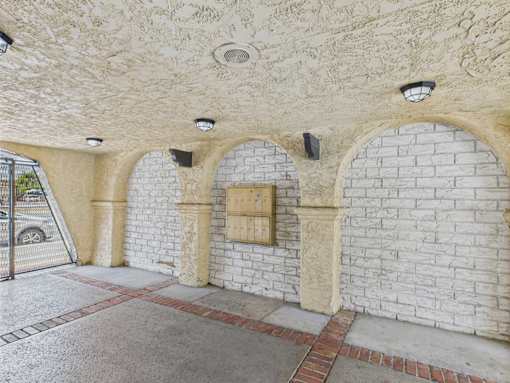A white brick wall with arches and a small window.