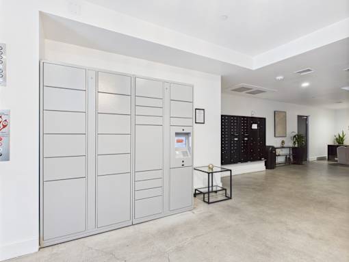 A room with a white wall and a grey floor with a white ceiling and a white cabinet with a black cabinet behind it.