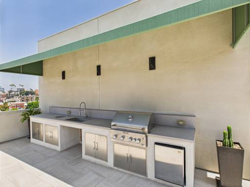 A modern outdoor kitchen with a grill, sink, and cabinets.
