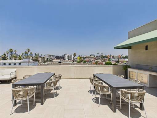 A table and chairs set on a patio with a view of the city.